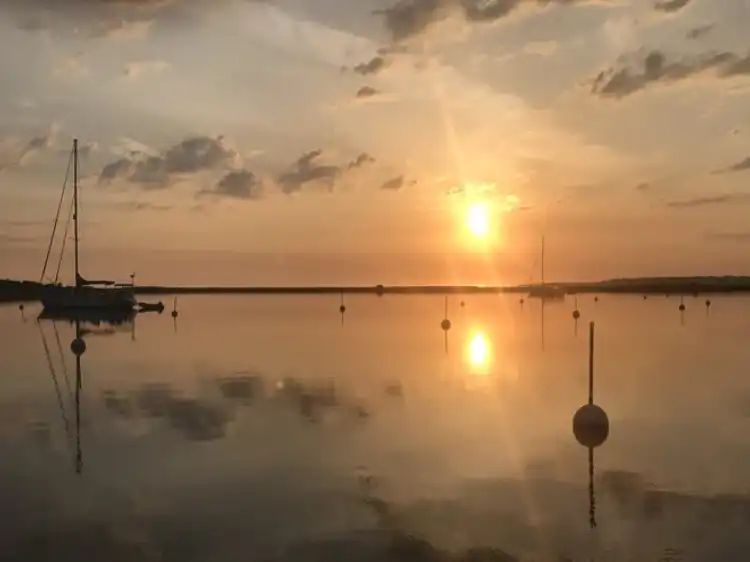 Sunset reflecting over calm water with soft clouds.