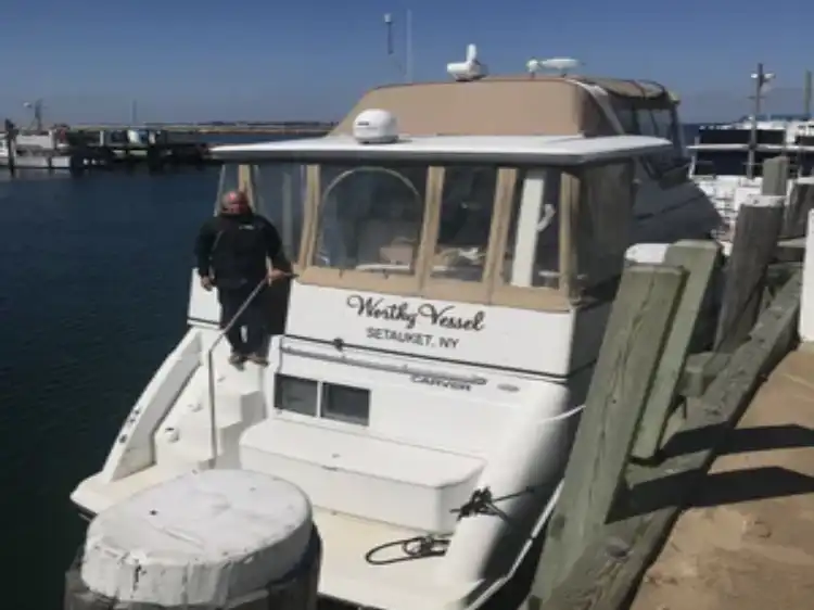 A man standing on a docked white yacht named "Steady Hand".
