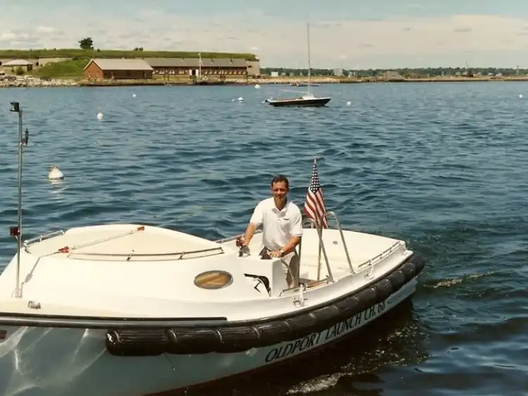 Man steering a small motorboat on a calm body of water.
