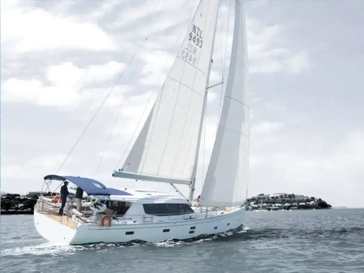 Sailboat gliding on calm waters with sails fully open.