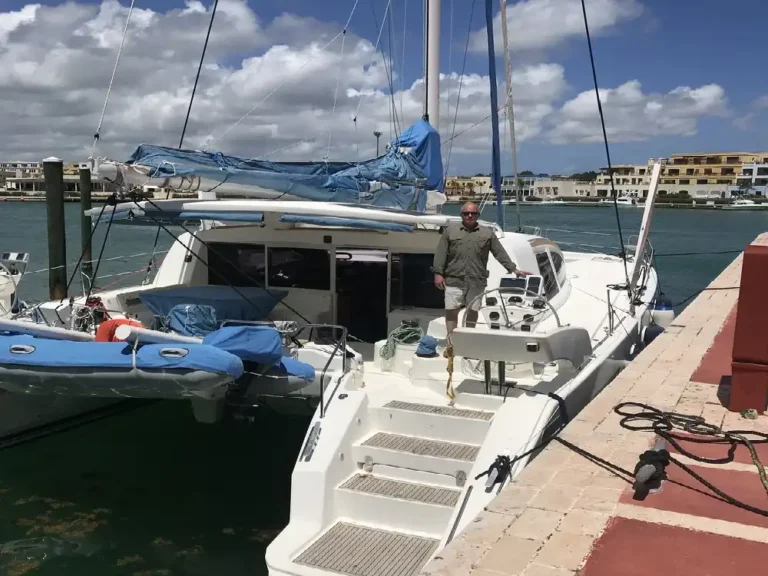 A cat relaxing on the back of a docked boat under a blue sky.