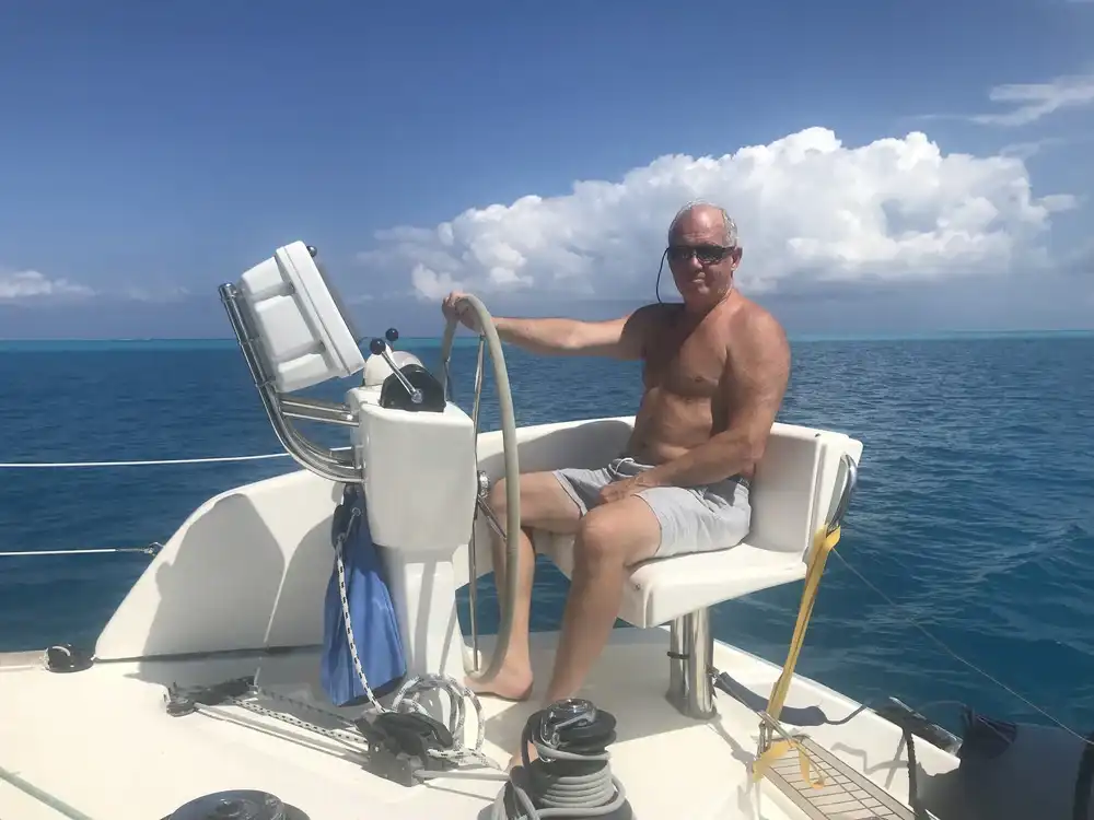 A man steering a boat on a sunny day at sea.