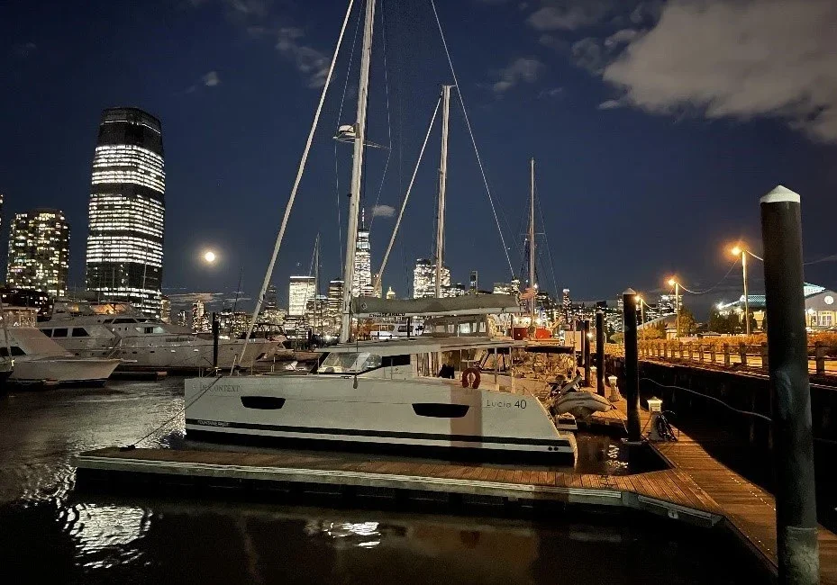 Sailboats docked at a marina under a cloudy night sky.