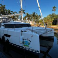 White catamaran docked at a marina on a sunny day.