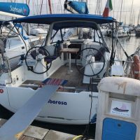Modern sailboat docked at a marina with twin steering wheels.