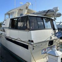 A white yacht docked at the marina with a covered upper deck.