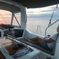 Person relaxing on a boat at sunset over calm waters.