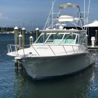 White motor yacht docked at a marina on a calm day.