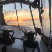 Sunset view from a boat cockpit with sailing equipment visible.