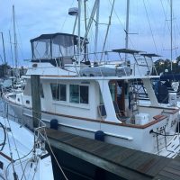 A white motor yacht docked at a marina with other boats nearby.