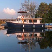 A classic wooden boat docked by the calm water with clear reflections.