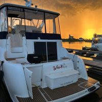 A luxury white yacht docked at sunset with calm water reflections.