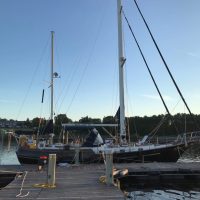 Sailboats docked at a serene marina during sunset.