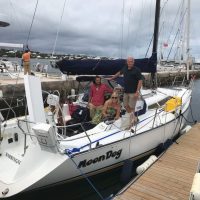 Group of people celebrating on a sailboat docked at a marina.