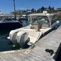 A sleek white motorboat docked at a marina under clear skies.