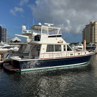 A luxury yacht docked at a marina under a blue sky.