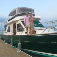 Couple standing on a yacht docked at a marina.