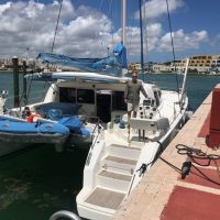A sailboat docked at a marina under a partly cloudy sky.